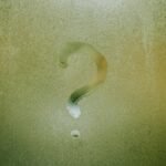 A question mark drawn on foggy glass, evoking curiosity and mystery.