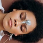 Woman practicing meditation with healing crystal on forehead, promoting wellness and relaxation.