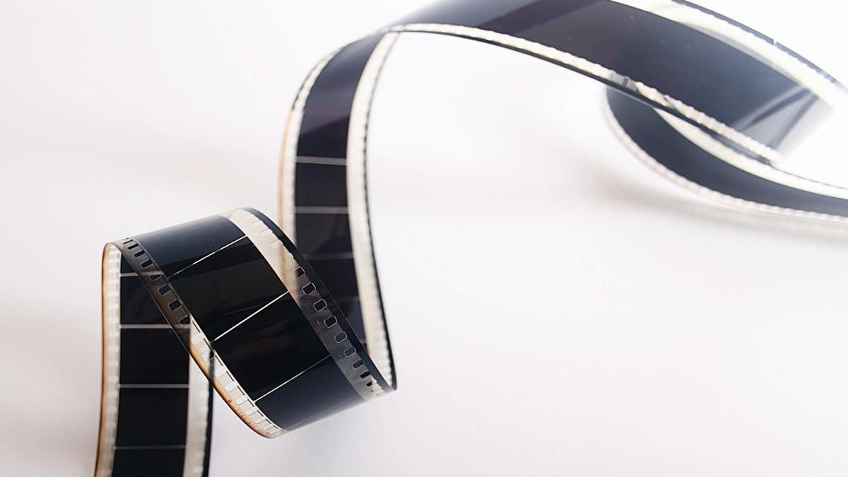 Close-up of a curled filmstrip against a white background, emphasizing vintage cinema.