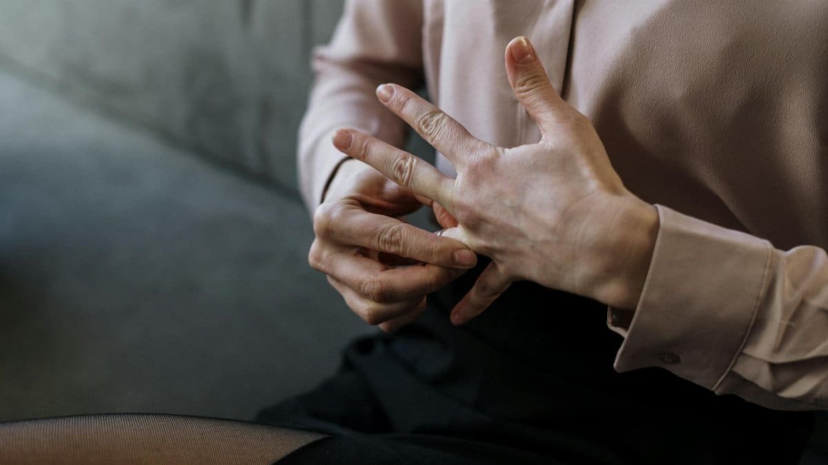 Close-up of a person removing a wedding ring, symbolizing relationship change or decision.