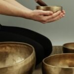 A person using bronze singing bowls for meditative sound therapy in a calm setting.