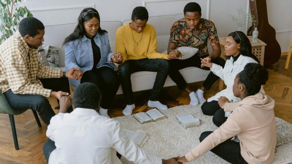 A group of people holding hands in prayer, creating a sense of unity.