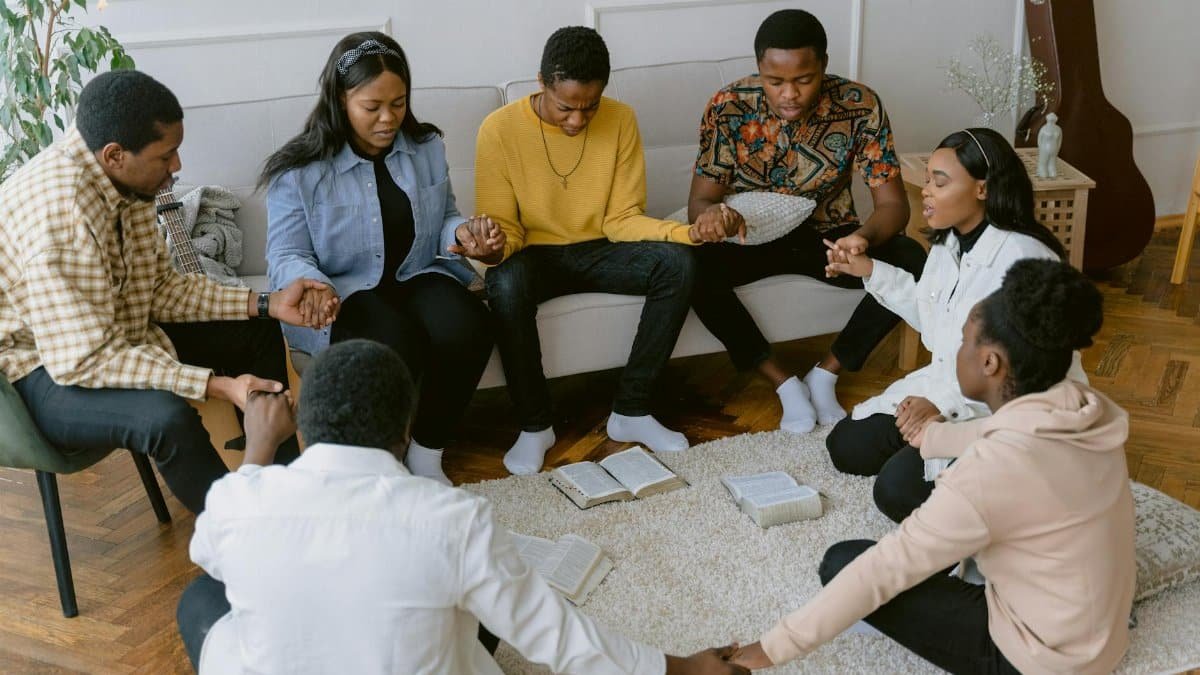A group of people holding hands in prayer, creating a sense of unity.