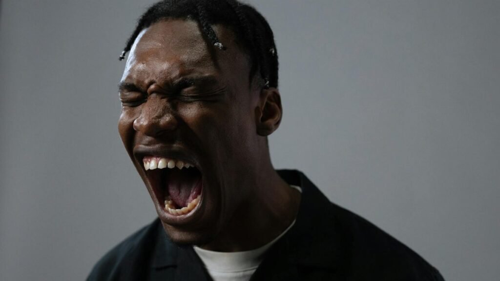 A powerful portrait capturing a man in a moment of intense emotion, possibly anger or frustration.