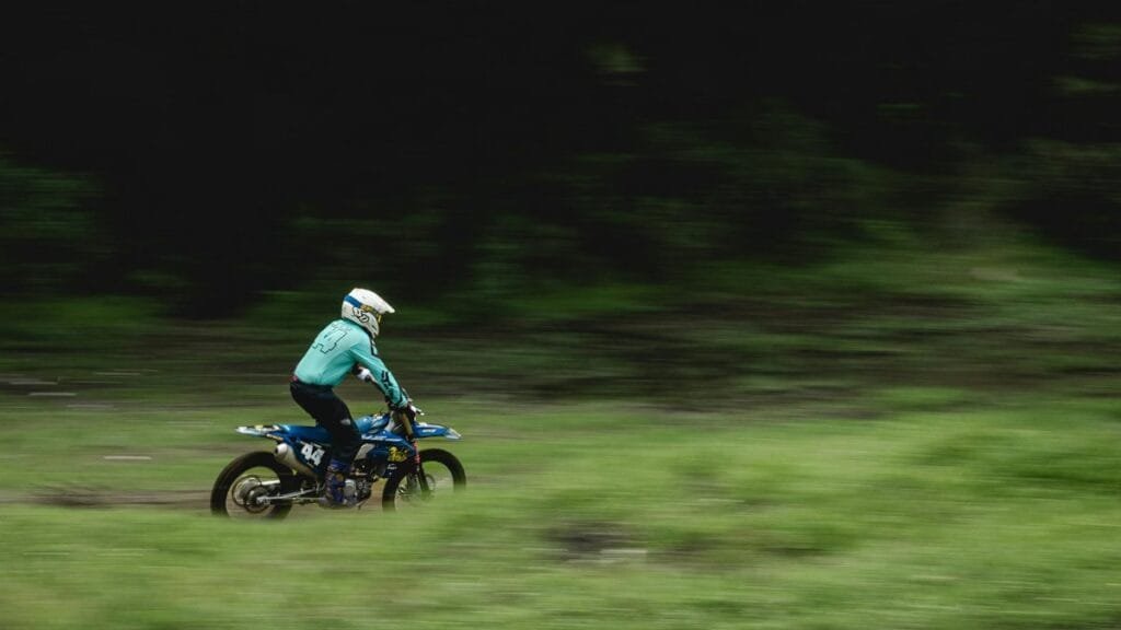 Motorcyclist performs high-speed dirt biking on an outdoor track, captured in motion.