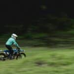 Motorcyclist performs high-speed dirt biking on an outdoor track, captured in motion.