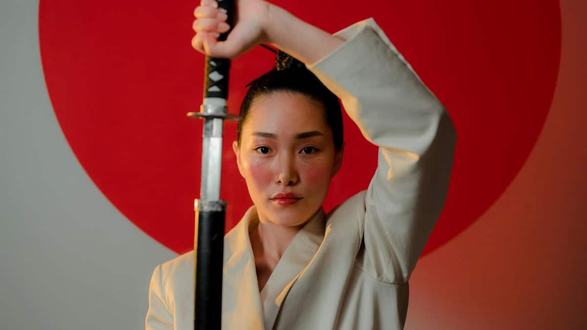 A striking portrait of a resilient woman in a blazer holding a katana, emphasizing strength and elegance.