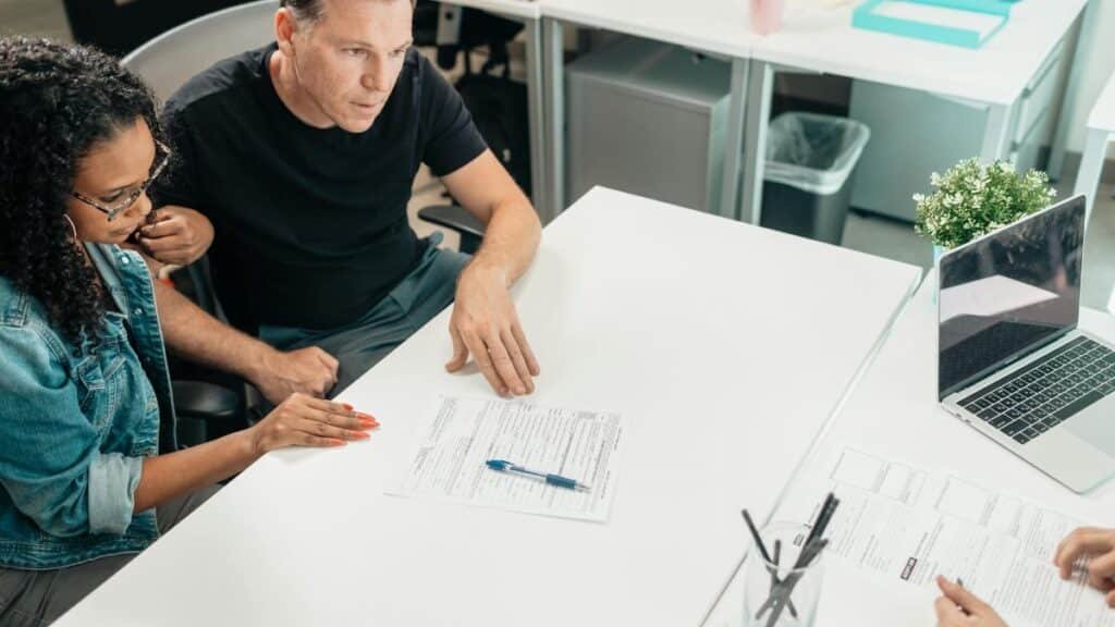A couple discusses legal documents with a professional in a modern office setting.