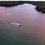 A stunning aerial view of boats gliding on a serene lake in Mound City, Kansas, surrounded by lush greenery.