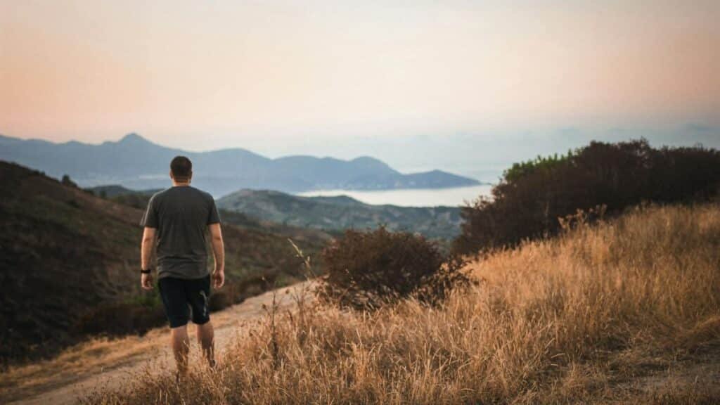 Man walking along a path in Kerkera, Algeria, amidst scenic mountains at sunset.