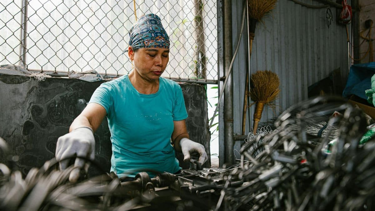 A woman working in a recycling facility sorting metal items. Industrial and labor scene.