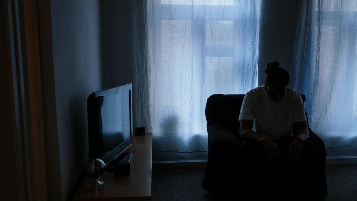 A person sits alone in a dimly lit room, reflecting solitude and moodiness.