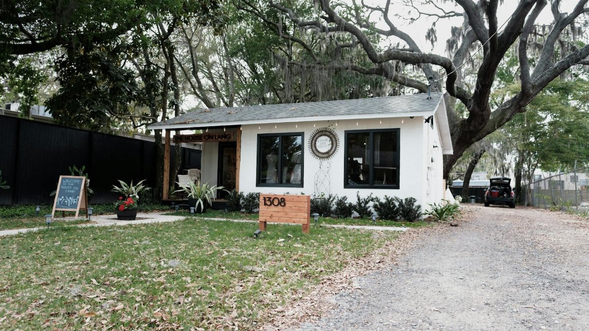 Cozy white house with rustic charm surrounded by mossy oak trees, located in Orlando, Florida.