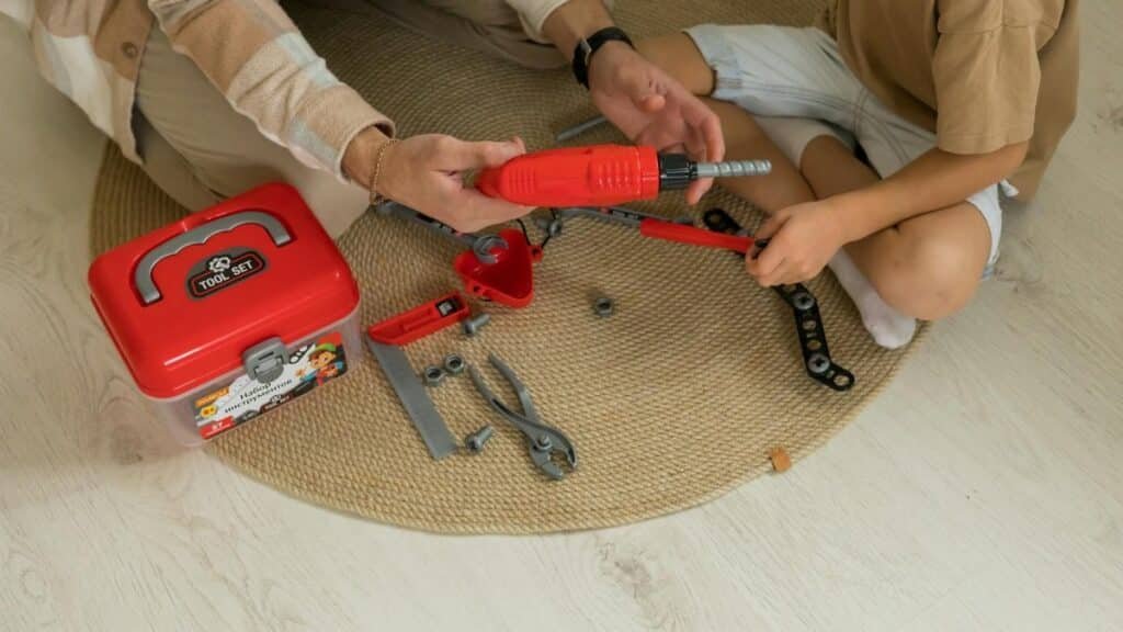 A father and son bonding over a toy tool set indoors, fostering creativity and learning.