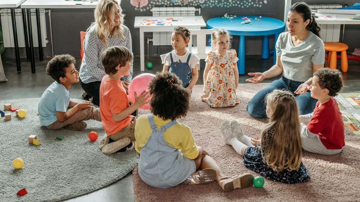 Children in circle time with teachers, engaging in a kindergarten classroom activity.