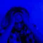 Portrait of a distressed person under dramatic blue lighting, expressing mental anguish.