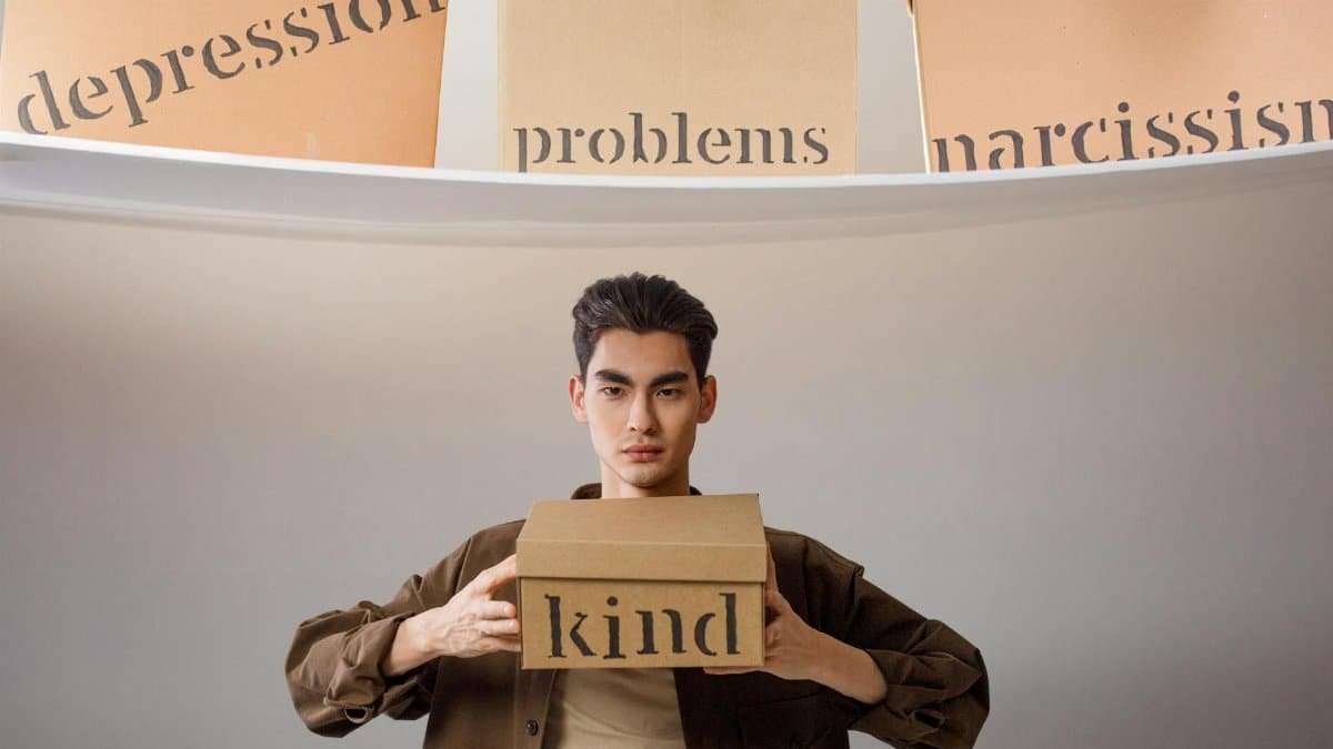 Creative image depicting a person balancing emotional concepts represented on cardboard boxes.