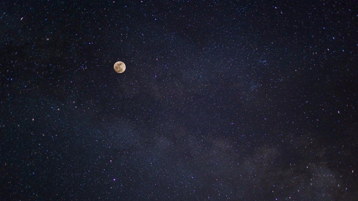 A breathtaking view of the full moon against a starry night sky with the Milky Way.