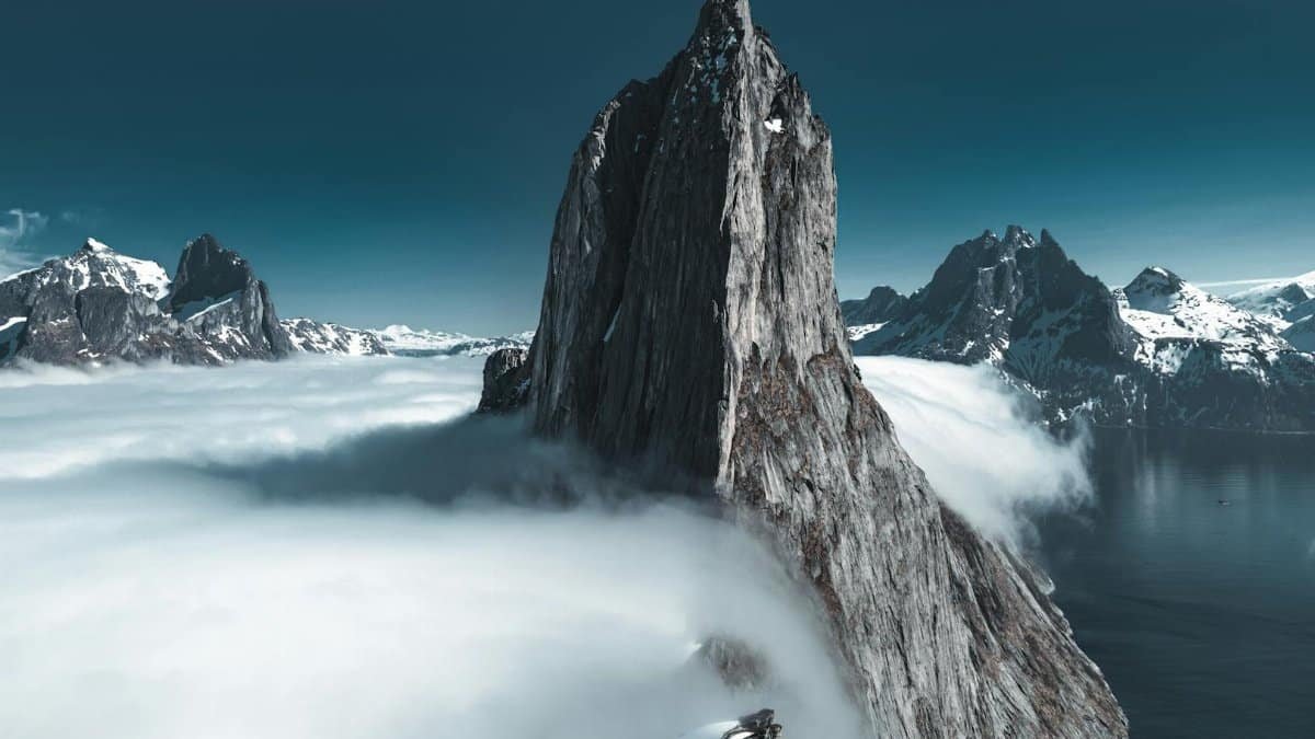 A stunning, snow-capped mountain peak rising above the clouds, creating an epic natural landscape.