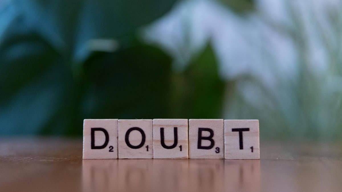 Close-up of Scrabble tiles spelling 'doubt' on a wooden surface, conveying uncertainty.