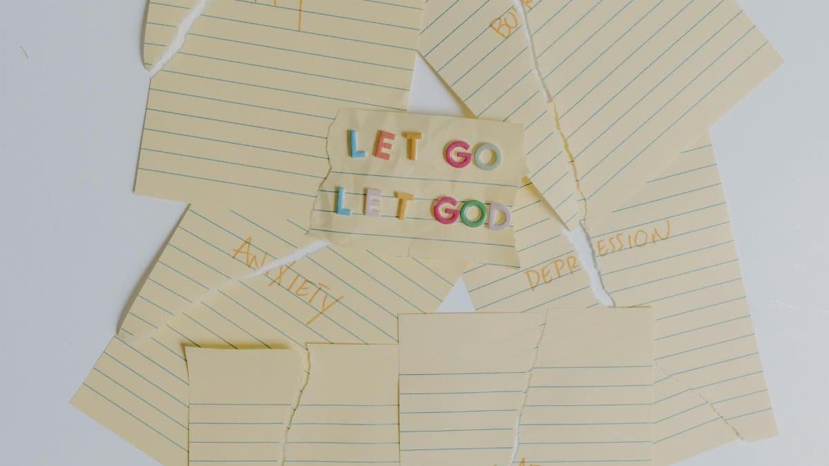 Flat lay of torn notes with an inspirational 'Let Go, Let God' message.
