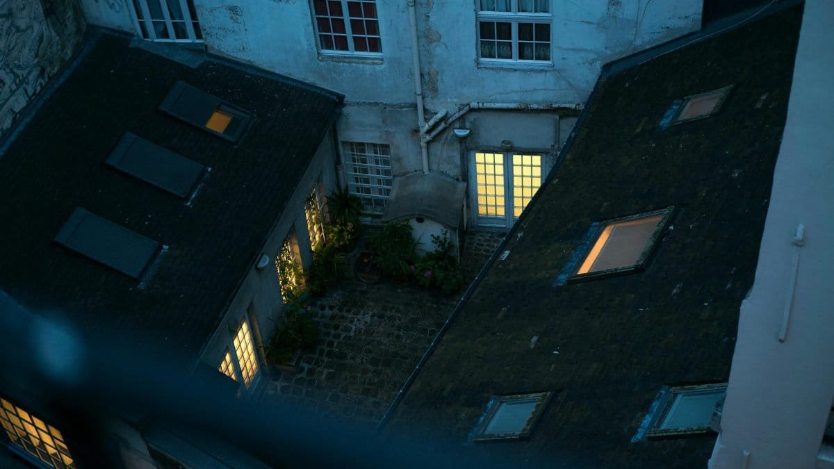 A serene view of cozy rooftops and lit windows in an old town during twilight.