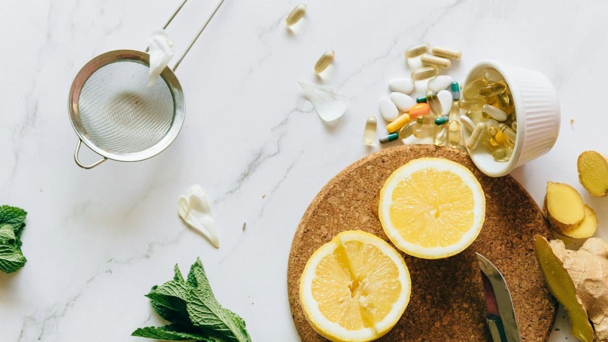 Flat lay of lemon, ginger, and supplements on a marble surface, illustrating natural remedies.