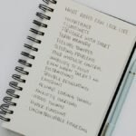 Notebook open with handwritten list of ADHD symptoms, featuring a pen alongside.