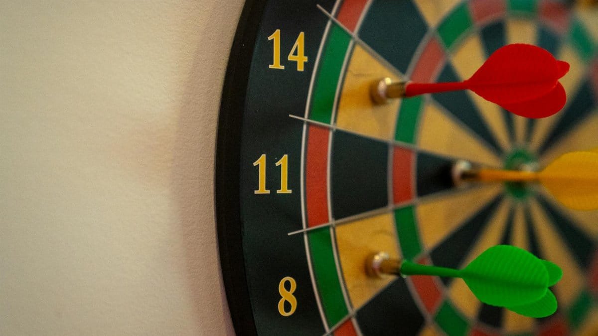 Vivid close-up of a dartboard with multicolored darts accurately striking the target.