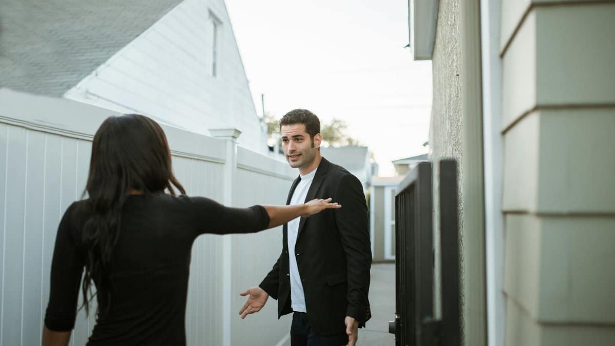 Man and woman having an argument in a suburban alleyway during the day.