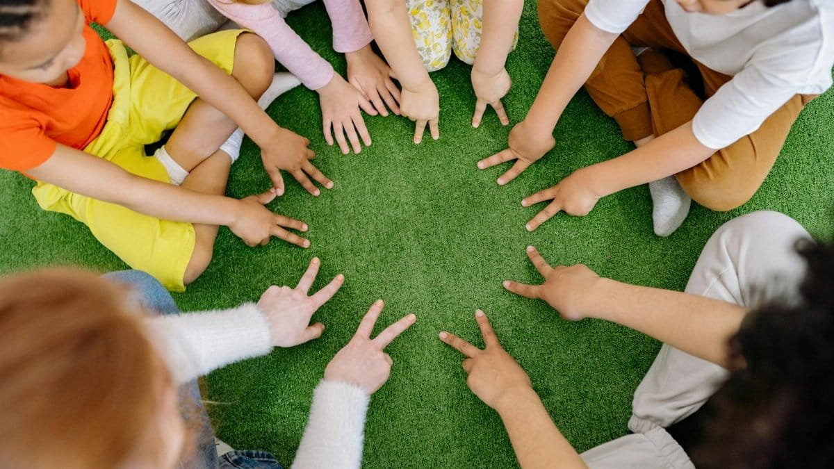 Children sitting in a circle playing fun team games on artificial grass.