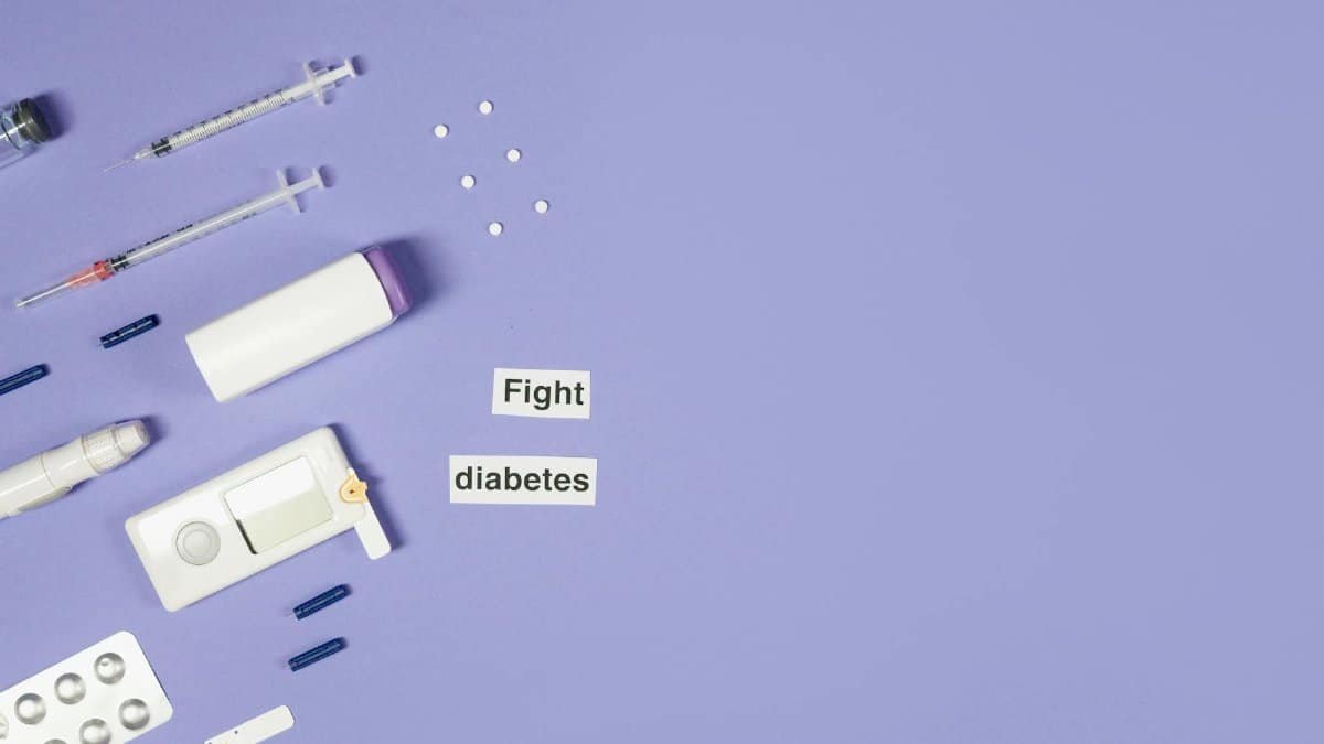 A flat lay of diabetes management tools, including syringes and pills, on a purple background.