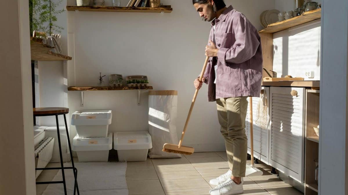 A man in casual attire cleans a stylish kitchen, emphasizing eco-friendly living.