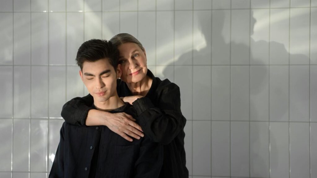 A mother lovingly embraces her son in a serene indoor setting, capturing a heartfelt moment.