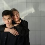 A mother lovingly embraces her son in a serene indoor setting, capturing a heartfelt moment.