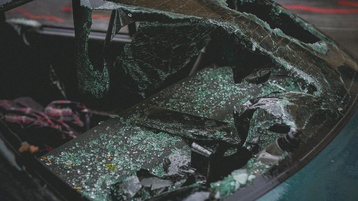 Detailed view of shattered car windshield after accident, emphasizing damage and broken glass.