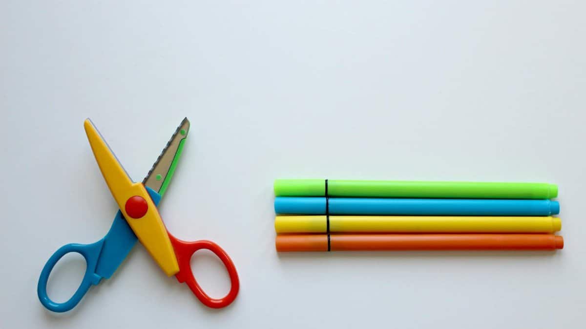 Bright stationery set on a white background with colorful scissors and markers.