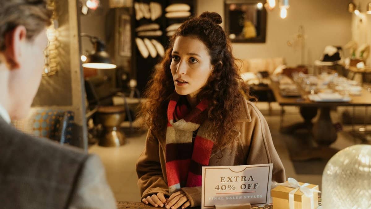 Woman in a boutique store discussing with a salesperson during a sale.