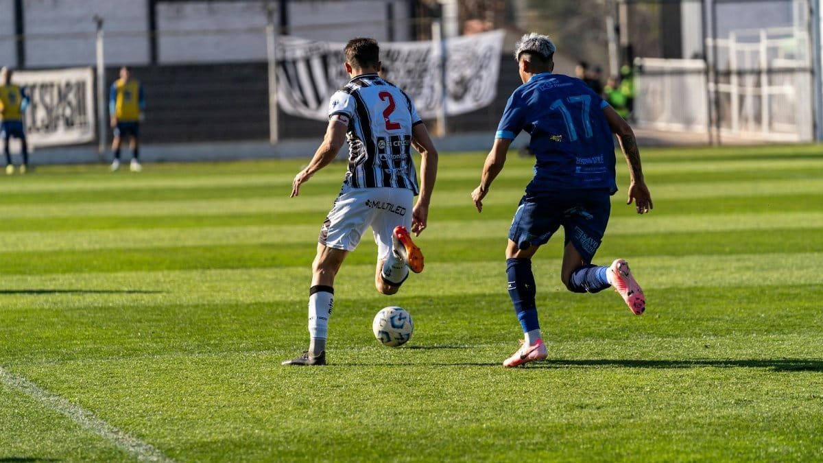 Two soccer players compete fiercely on a sunny field, showcasing athleticism and sportsmanship.