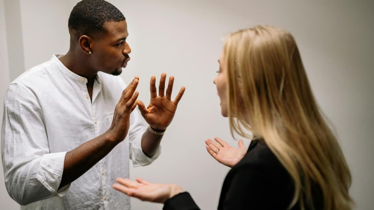 Frustrated coworkers in heated discussion, expressing disagreement in office setting.
