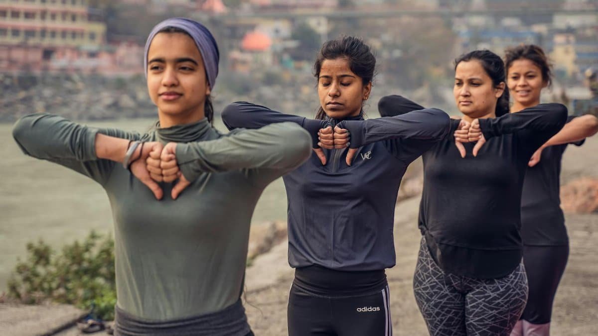 Women practicing yoga together on the riverbank in Rishikesh, India, promoting wellness and mindfulness.