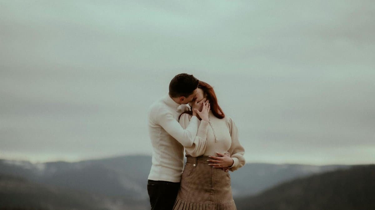 A couple shares an affectionate embrace against a scenic autumn landscape in Beliș, Romania.