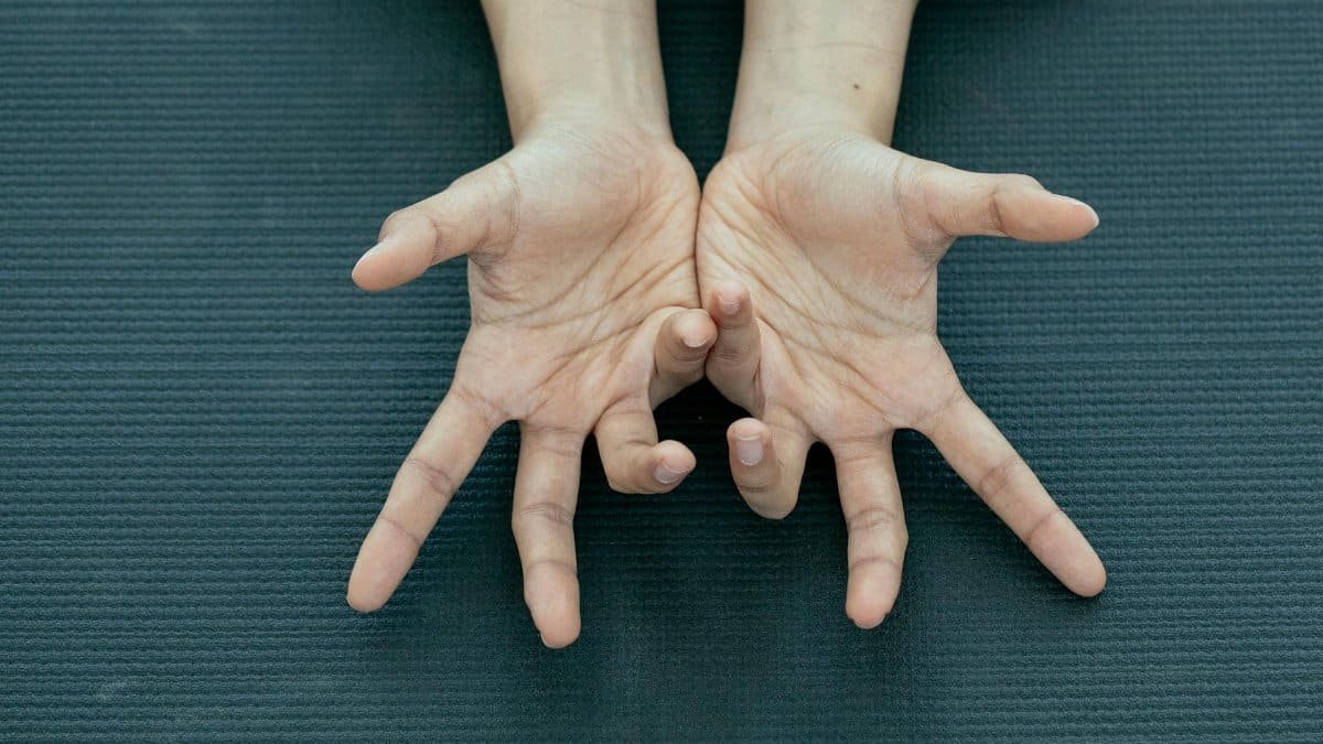 Overhead view of an expressive hand gesture against a textured mat background, showcasing creativity and movement.