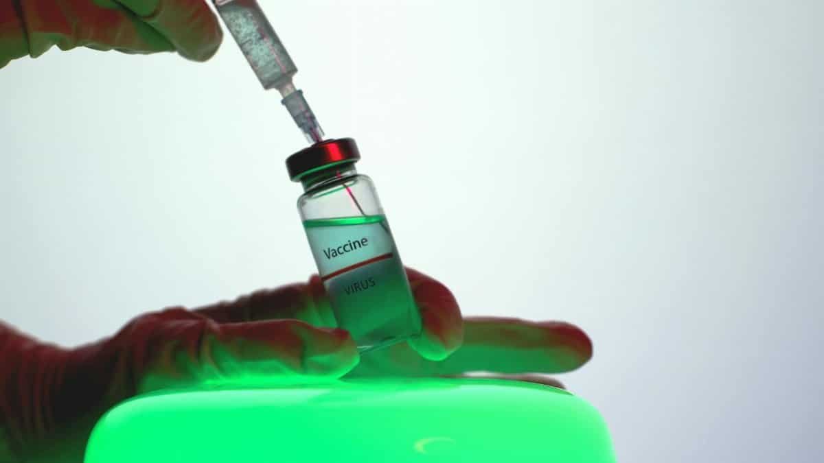 Syringe drawing vaccine from vial, symbolizing immunization efforts.