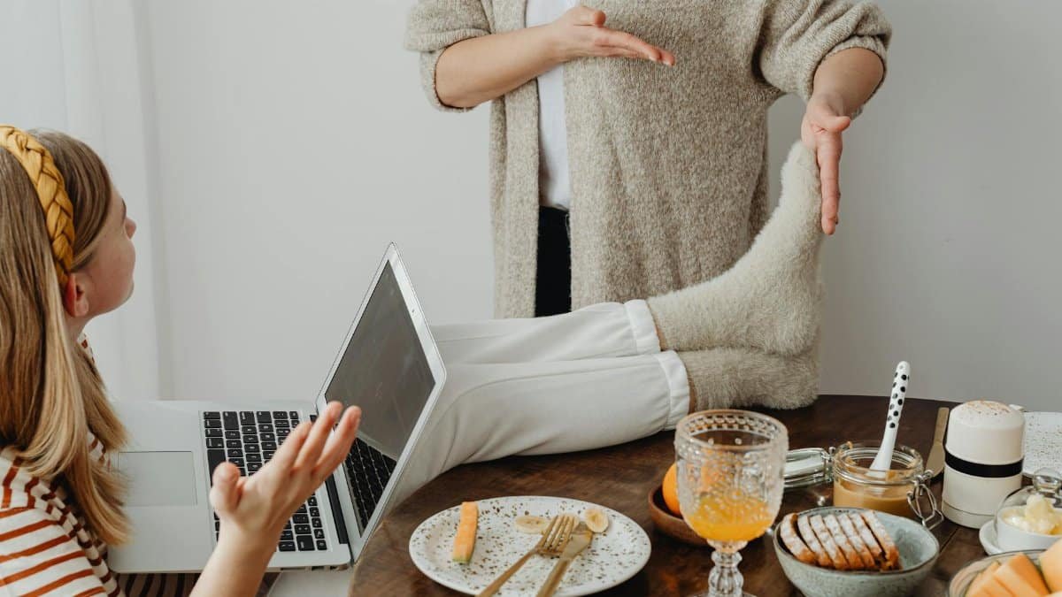 Woman relaxing with laptop on dining table, showcasing casual home life.