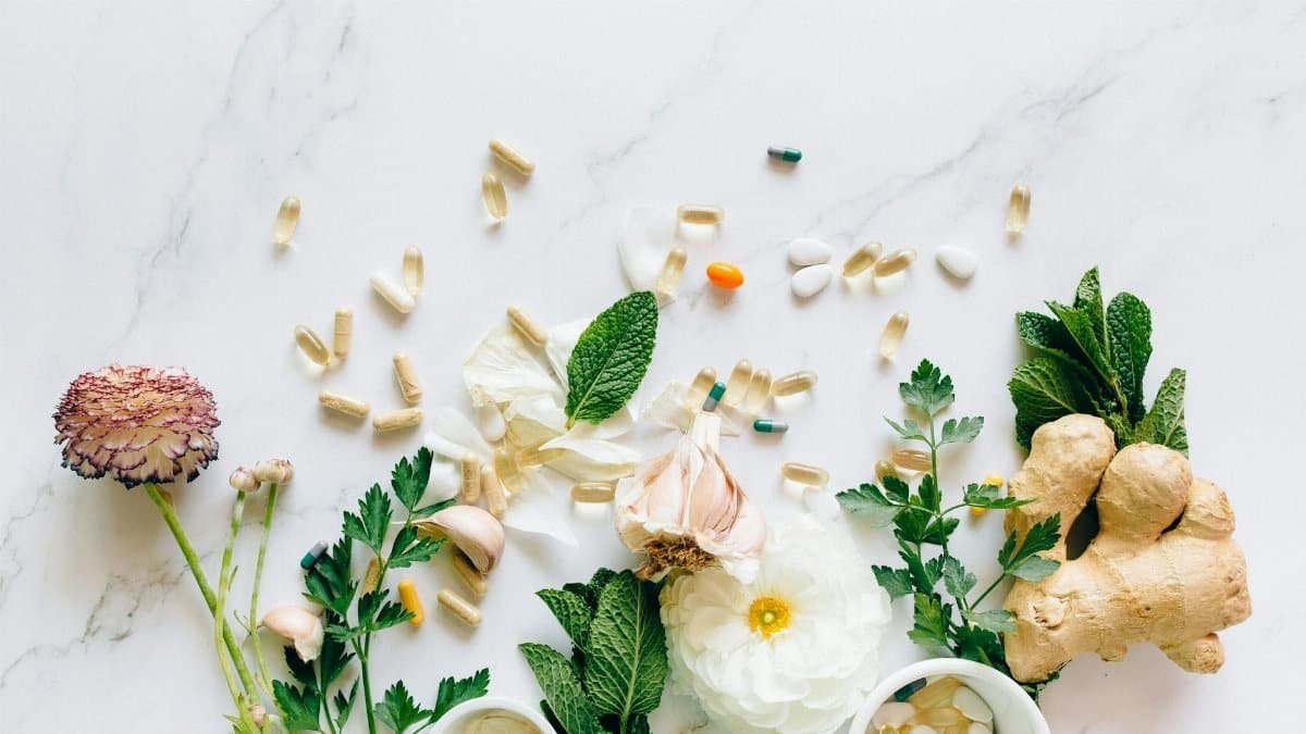 Natural herbs and pills arranged on a marble surface for a holistic healthcare theme.