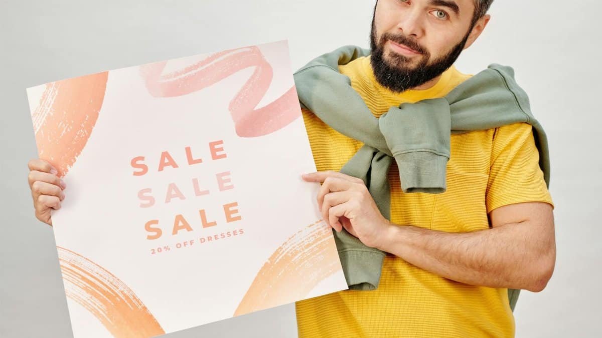Man holding a sale poster advertising 20% off dresses. Perfect for Black Friday promotions.