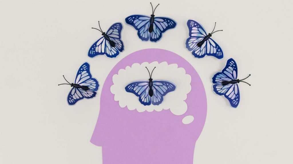 Creative illustration of butterflies representing thoughts over a brain silhouette.