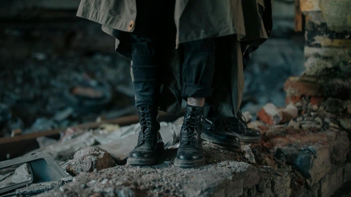 Dark atmospheric image of boots on rubble in a desolate urban setting.