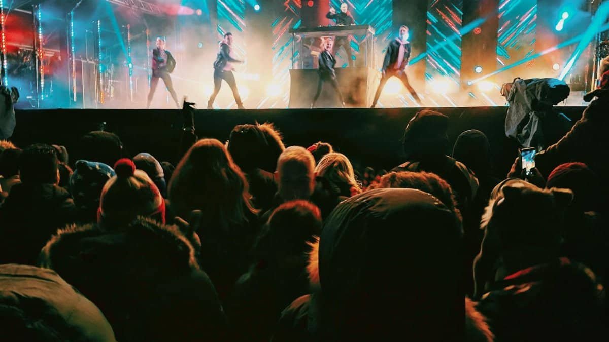 Energetic concert crowd enjoying a nighttime performance in Helsinki with vibrant lights and performers.